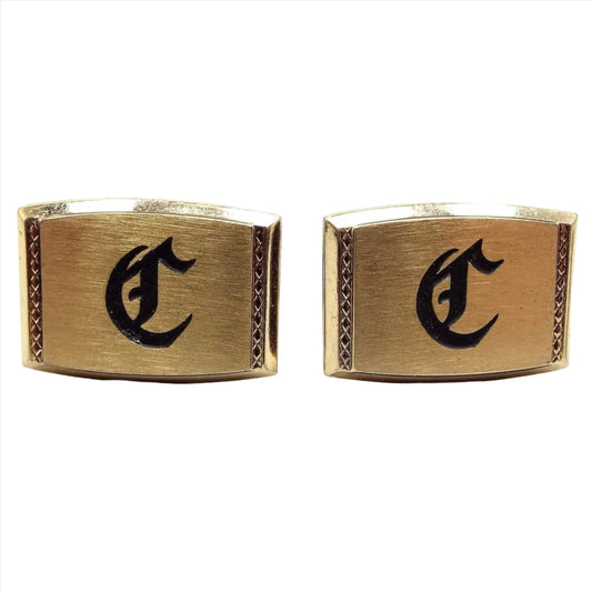 Front view of the Mid Century Vintage Hickok cufflinks, they are rectangle in shape with rounded top and bottom and are gold tone in color. The fronts have a fancy initial letter C engraved on the front that is painted in black.