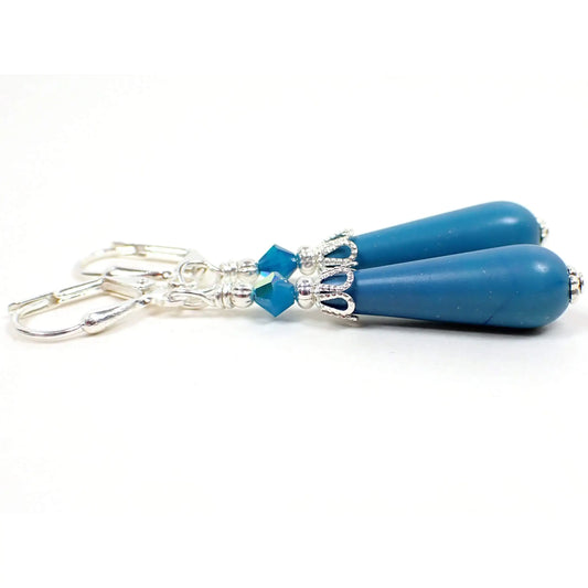 Side view of the handmade teardrop earrings with vintage lucite beads. The metal is silver plated in color. There are new opaque blue faceted glass beads at the top. The bottom vintage beads are teardrop shaped and are turquoise blue color lucite.