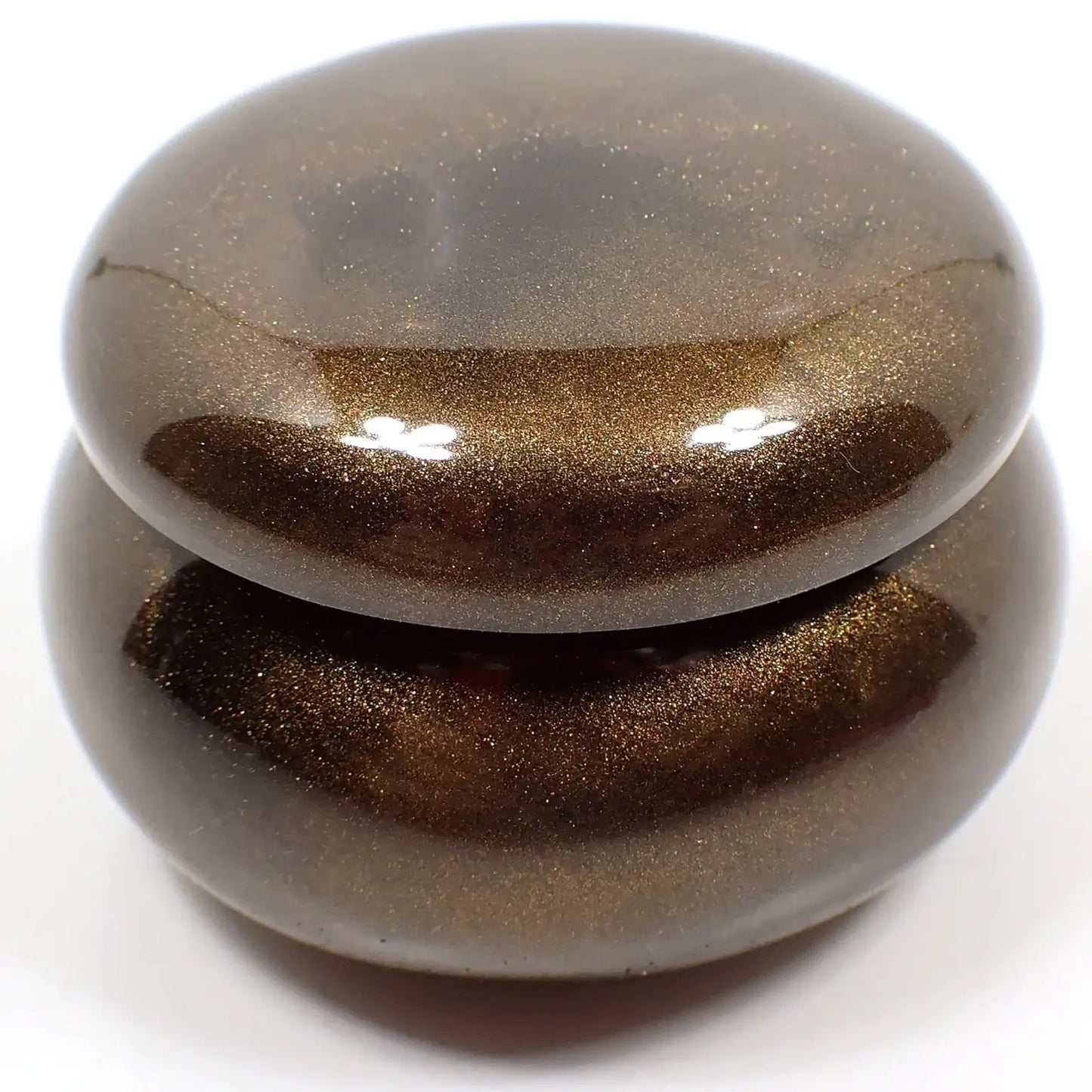 Side view of the smaller sized handmade resin trinket box. It has a rounded wide jar like shape with a round lid. The resin is pearly chocolate brown in color.