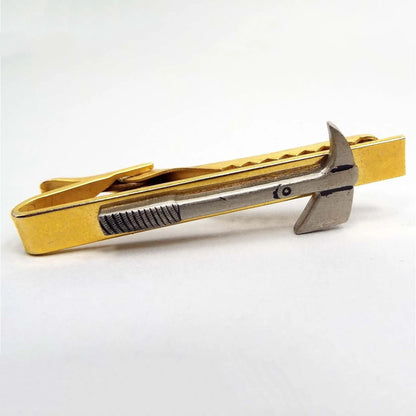 Front view of the retro vintage fireman's hatchet Prandi axe tie clip. The tie clip part is gold tone in color. The axe on the front is a light pewter gray.