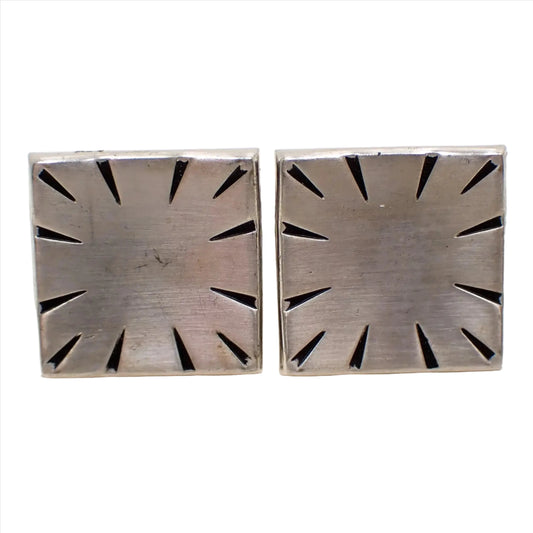 Enlarged front view of the Mid Century vintage Swank modernist cufflinks. The metal is matte silver tone in color. They are shaped like indented squares and have diagonal tapered etched and black painted lines around the edge for an antiqued silver tone appearance.