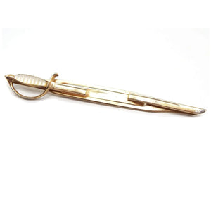 Front view of the Mid Century vintage Swank sword tie bar. It is gold tone in color and shaped like a rapier. The handle has a mother of pearl cab and the middle is open to slide the tie into.