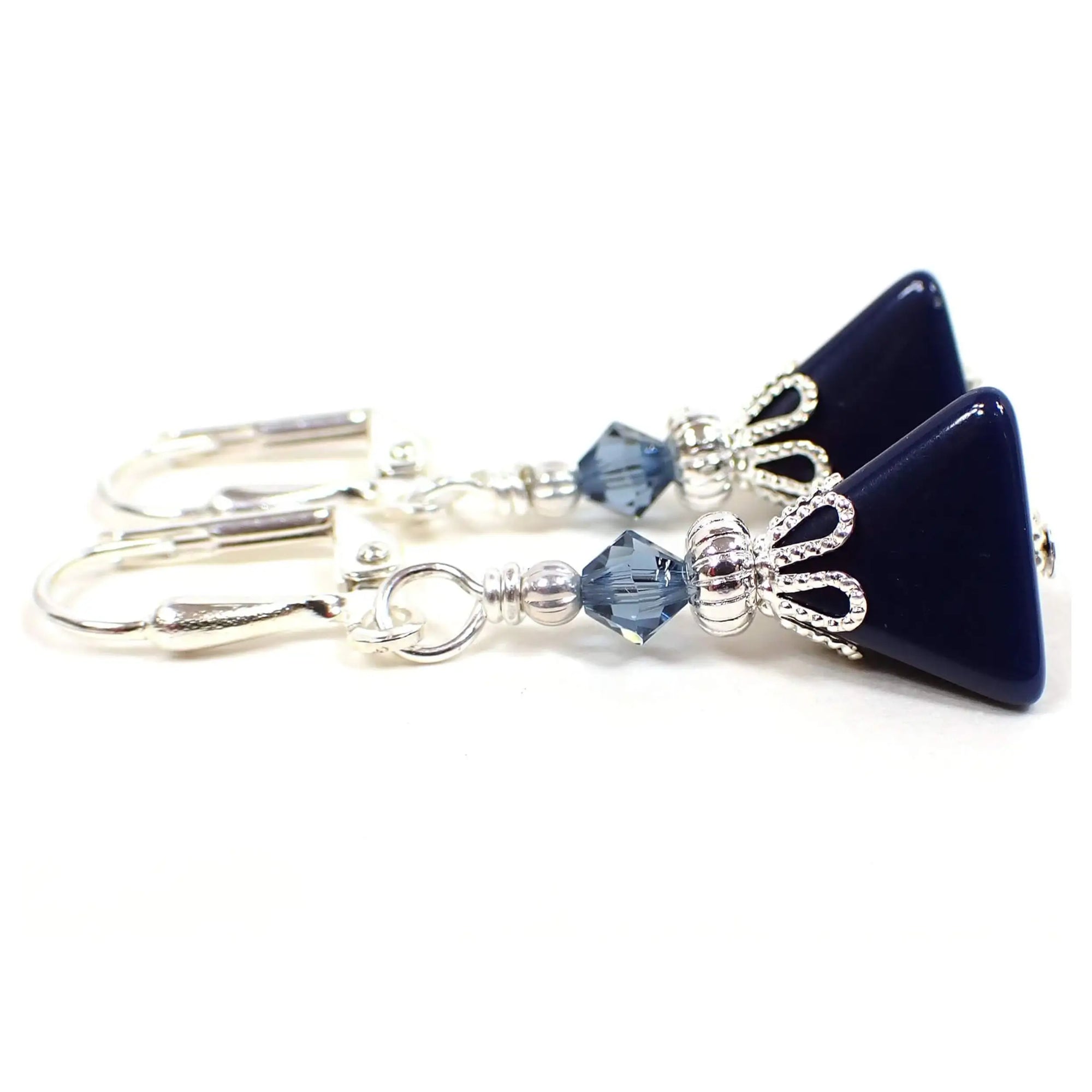 Side view of the small handmade pyramid earrings with vintage lucite beads. The metal is silver plated in color. There are new blue faceted glass crystal beads at the top. The bottom lucite beads are triangle pyramid shaped and dark blue in color.