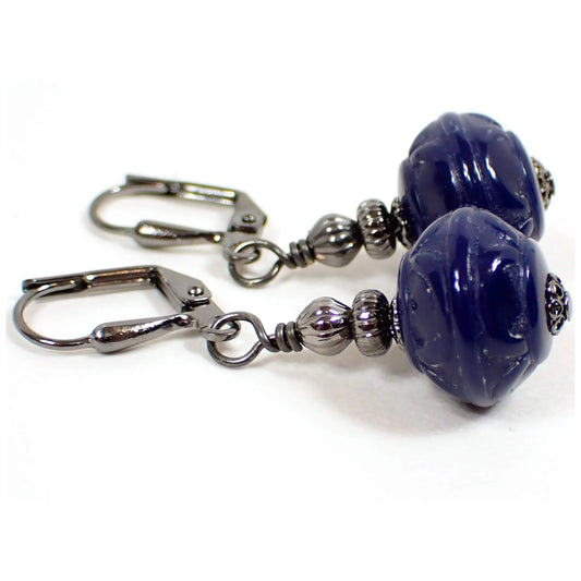 Side view of the handmade drop earrings with vintage lucite beads. The metal is gunmetal gray in color. The bottom lucite beads are rondelle shaped with a textured pattern and are dark blue in color.