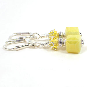 Side view of the handmade small cube earrings. The metal is silver plated in color. There are faceted glass crystal beads in yellow at the top. The bottom square cube beads are yellow glass with a golden sheen on the outside.