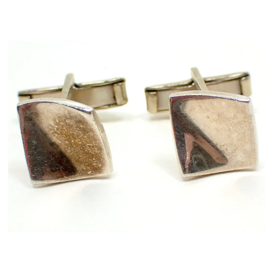 Enlarged front view of the retro vintage Mexican cufflinks. They are shaped like curved squares. The sterling silver has a darkened patina from age. You can see part of my reflection on the fronts from taking the photo.