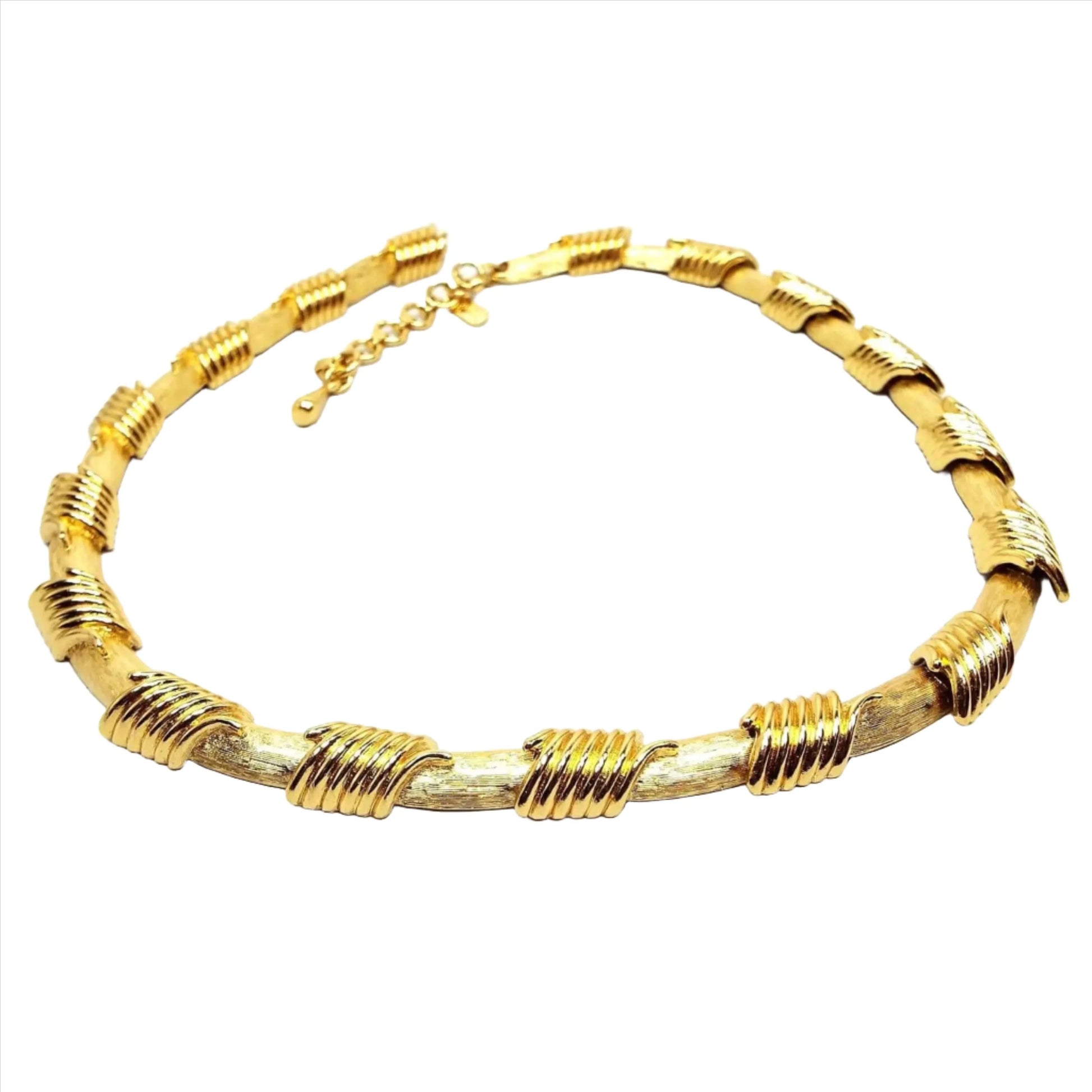 Front view of the Monet retro vintage link necklace. The metal is gold tone in color. There is a hook clasp at the end. The links have a matte brushed texture with shiny coil like areas above where the links join together.