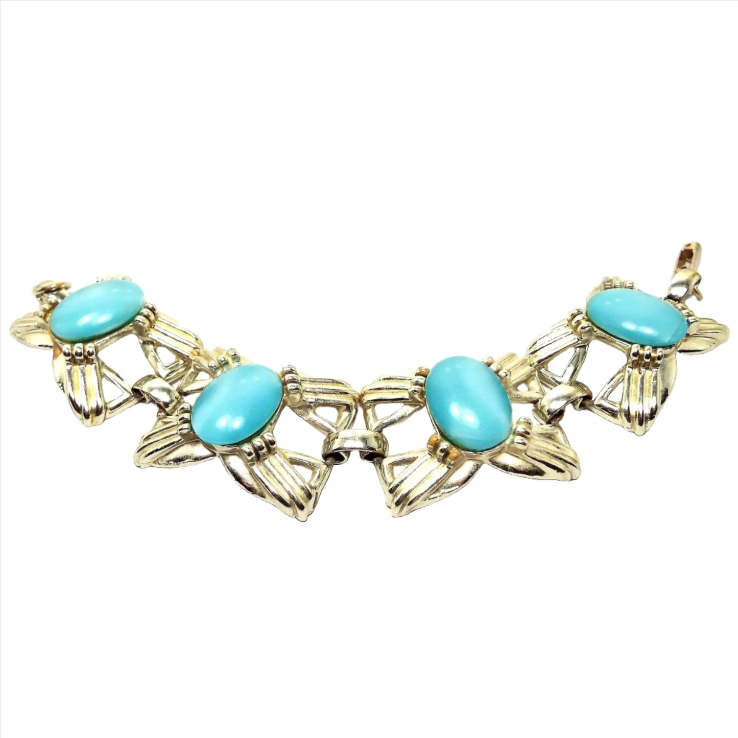 Top view of the Mid Century vintage link bracelet with glass faux cat's eye cabs. The metal is a light gold tone in color and has large bow like shaped open links. There are large oval glass cabs in aqua blue that have some flash as you move around in the light.