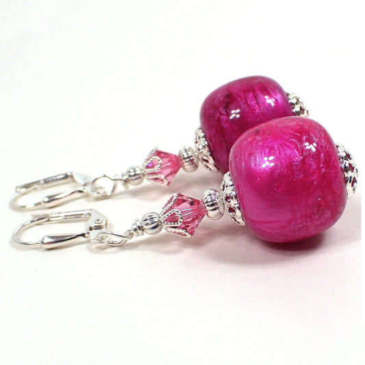 Side view of the handmade barrel drop earrings. The metal is silver plated in color. There are pink faceted glass crystal beads at the top. The bottom vintage lucite beads are swirled pearly raspberry pink in color and have a large barrel shape.
