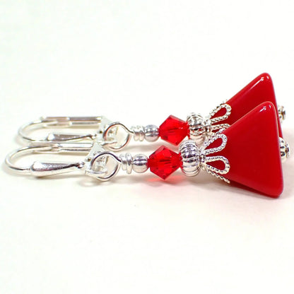 Side view of the small handmade pyramid earrings. The metal is silver plated in color. There are new red faceted glass crystal bicone beads at the top. The bottom beads are vintage lucite beads and are triangle pyramid shaped in a rich red color.