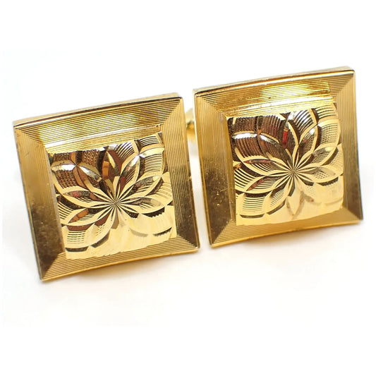 Front view of the retro vintage Atomic style cufflinks. They are gold tone plated in color and have a border with etched lines. The middle extends out in a square shape and has a diamond cut starburst pattern.