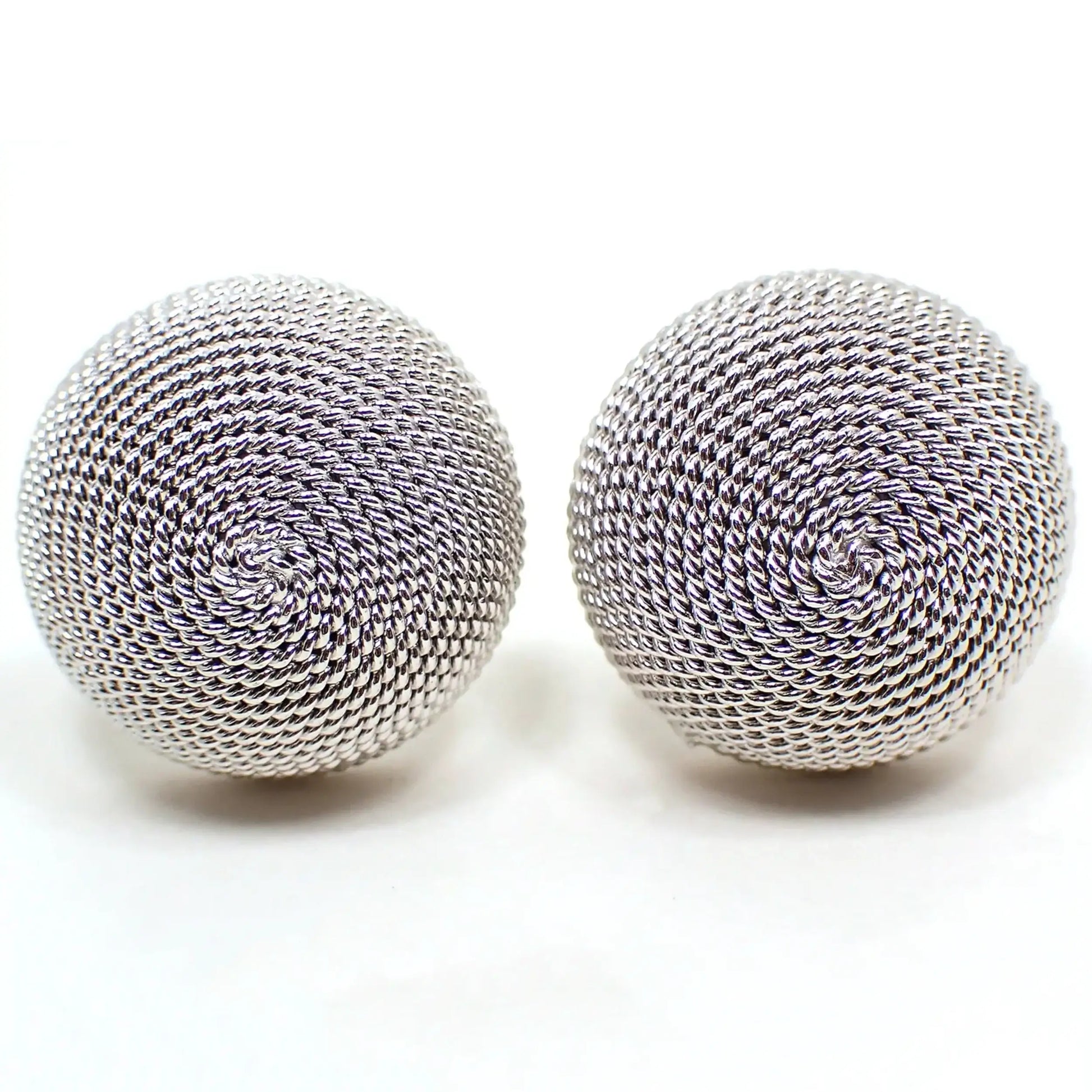 Enlarged front view of the retro vintage Shields cufflinks. They are round domed and silver tone in color. There is a twisted textured pattern that spirals around covering the fronts of the cufflinks.