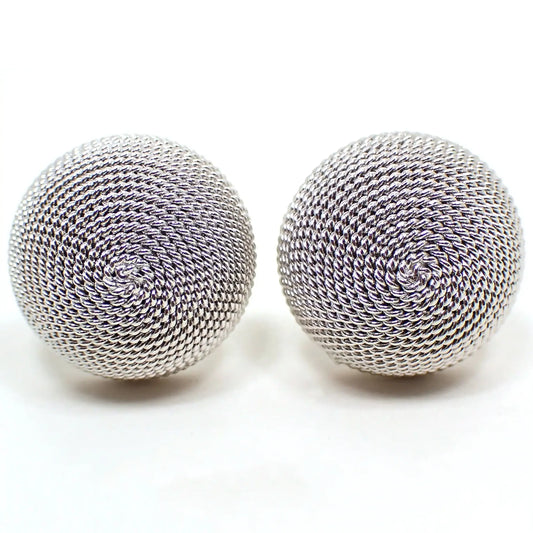 Enlarged front view of the retro vintage Shields cufflinks. They are round domed and silver tone in color. There is a twisted textured pattern that spirals around covering the fronts of the cufflinks.