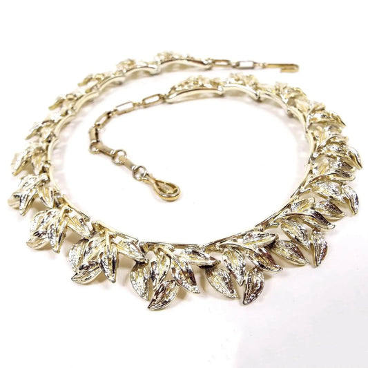 Front view of the 1960's. vintage Coro leaf link necklace. The metal on the choker is gold tone in color. Each link has a cluster of leaves hanging downward. There is a hook clasp at the end.