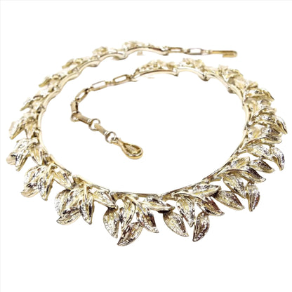 Front view of the 1960's. vintage Coro leaf link necklace. The metal on the choker is gold tone in color. Each link has a cluster of leaves hanging downward. There is a hook clasp at the end.