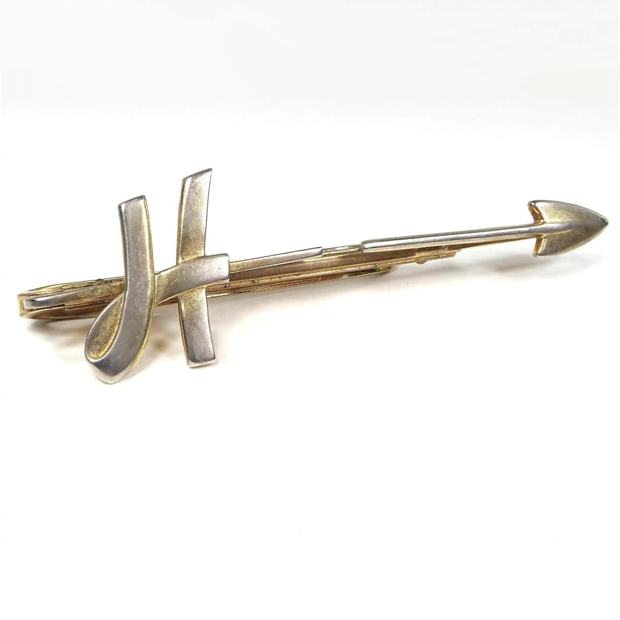 Front view of the Mid Century 1950's vintage Hickok initial tie bar. It is gold tone in color. There is a letter H on one side and an arrow head on the other. Each side has a hinge to open to put the tie under.