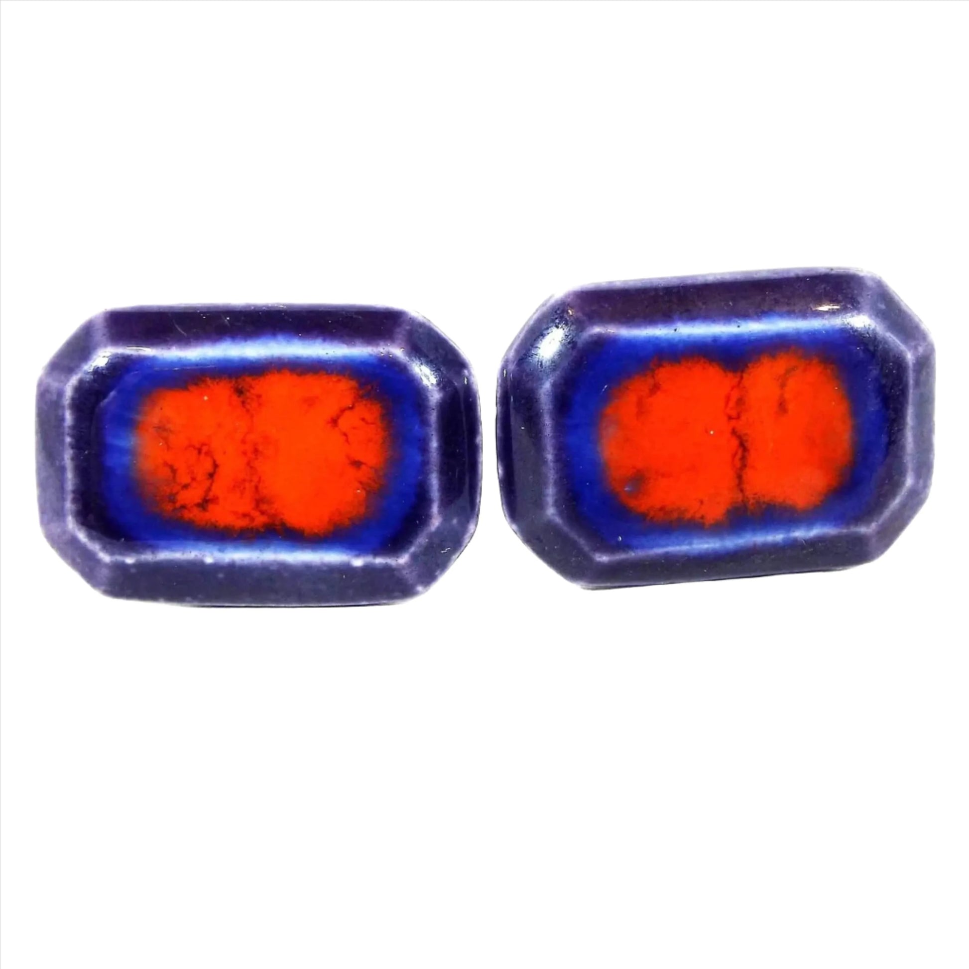 Front view of the retro vintage ceramic cufflinks. They are a long octagon shape with shades of dark and bright blue with bright red in the middle.