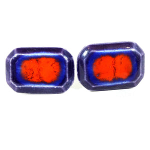 Front view of the retro vintage ceramic cufflinks. They are a long octagon shape with shades of dark and bright blue with bright red in the middle.