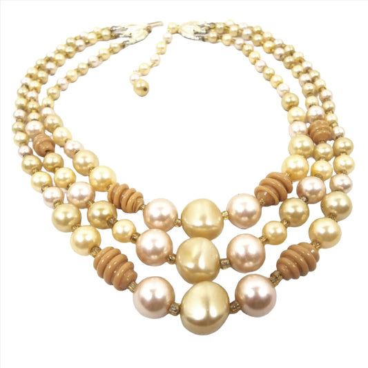 The Japanese Mid Century vintage multi strand beaded necklace. There are three strands of beads in yellow, mustard yellow, and very light pink with some hints of brown. There is a hook clasp at the end.