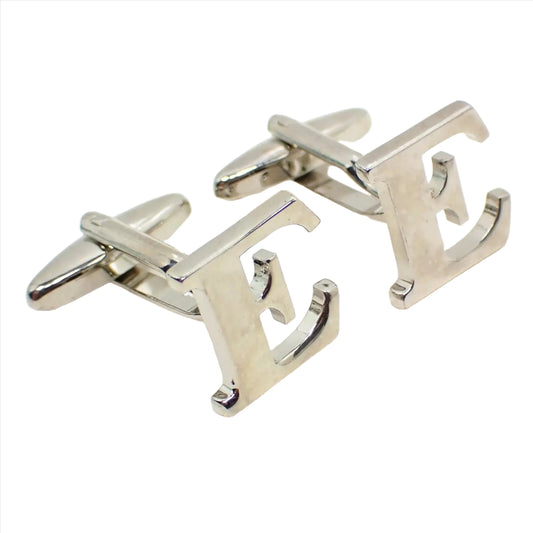 Enlarged angled view of the retro vintage initial cufflinks. They are silver tone in color and shaped like a block letter E.