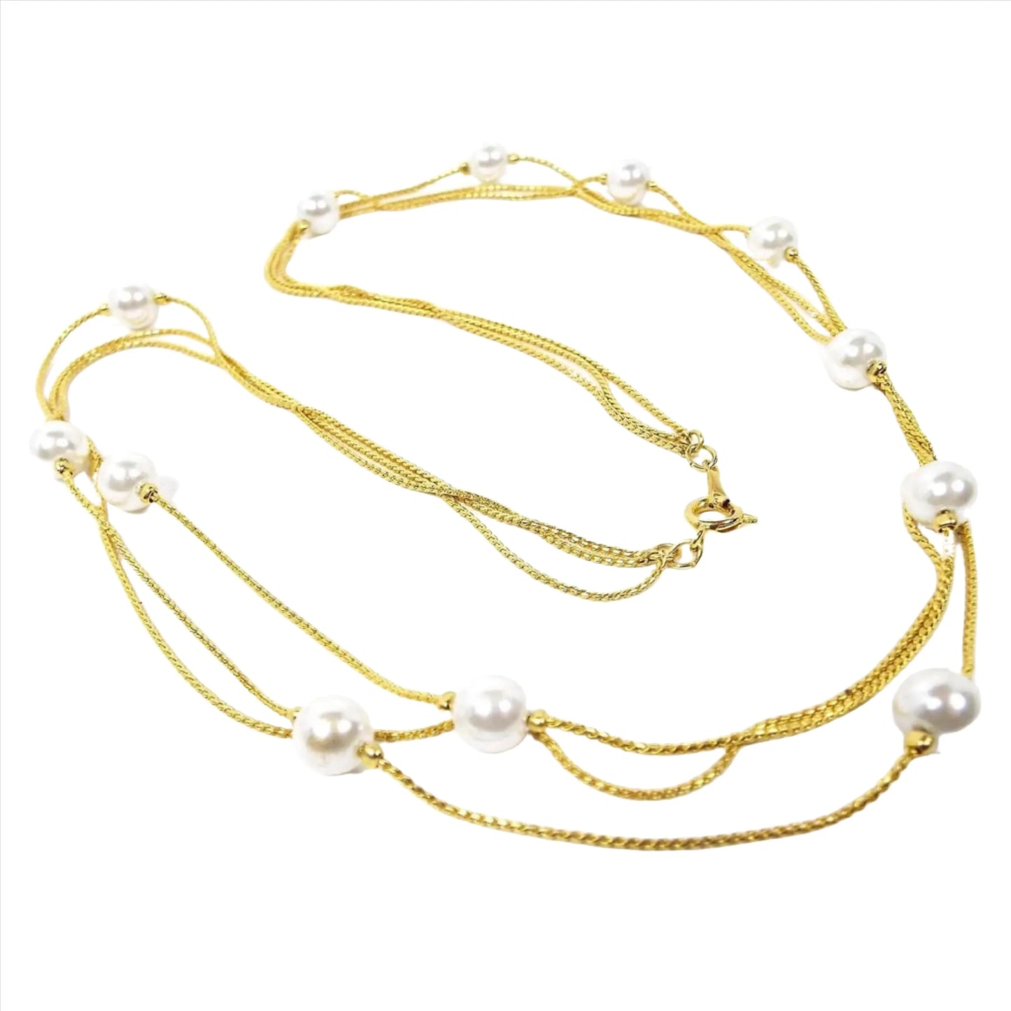 Retro vintage faux pearl beaded chain necklace. It has three thin strands of serpentine chain in gold tone color metal. The imitation pearl beads are scattered here and there throughout the necklace and are pearly white plastic. There is a spring ring clasp at the end.