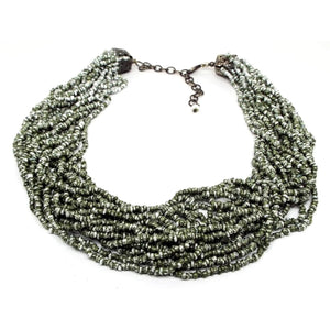 Front view of the retro vintage seed bead necklace. There are numerous strands of olive green and white speckled style seed beads. The end of the necklace has an antiqued bronze color chain and lobster claw clasp.