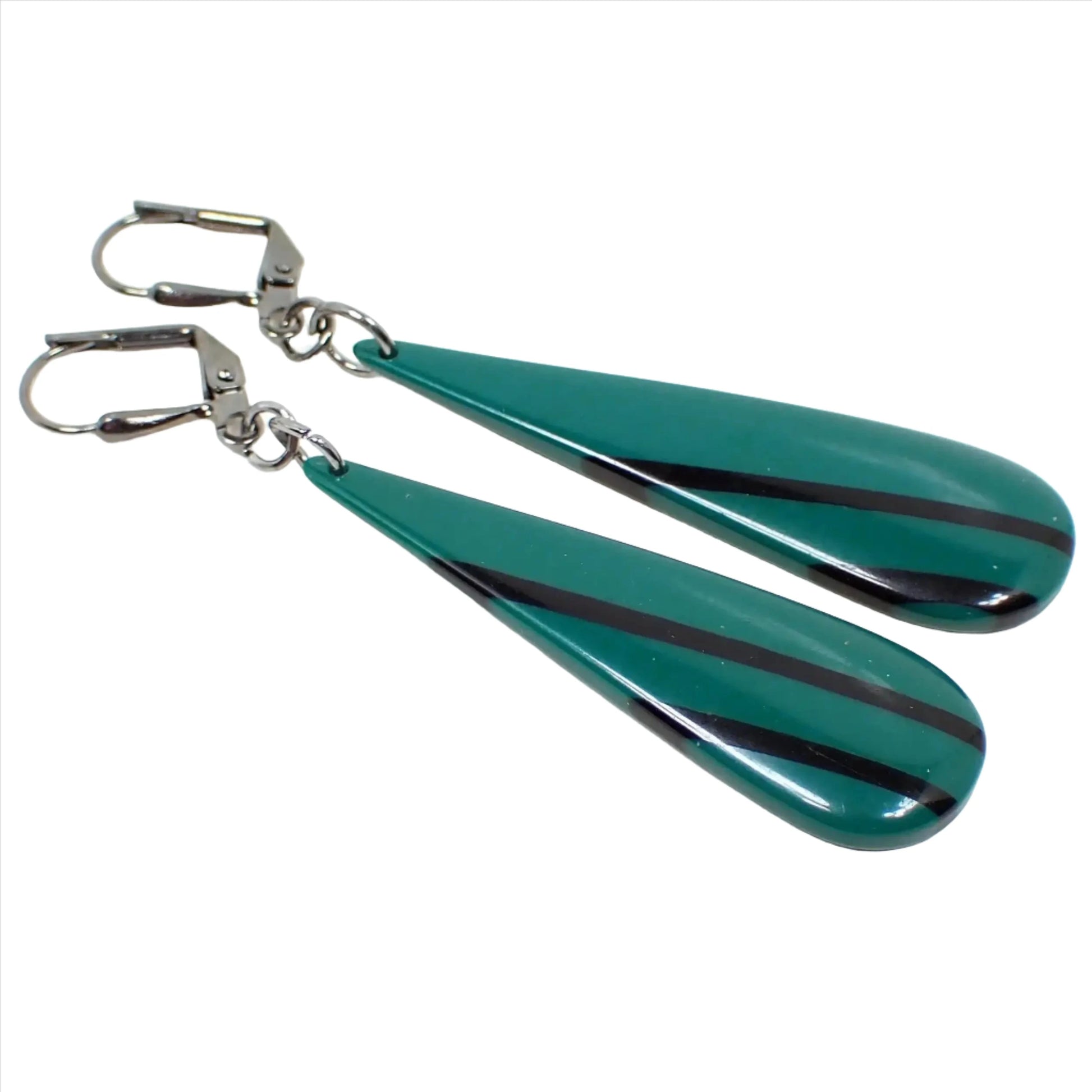 Angled enlarged view of the handmade drop earrings made with vintage resin beads. The metal is gunmetal gray in color. There are long thinner style teardrop beads that are slightly domed on the front. They are a darker green in color with black diagonal stripes.