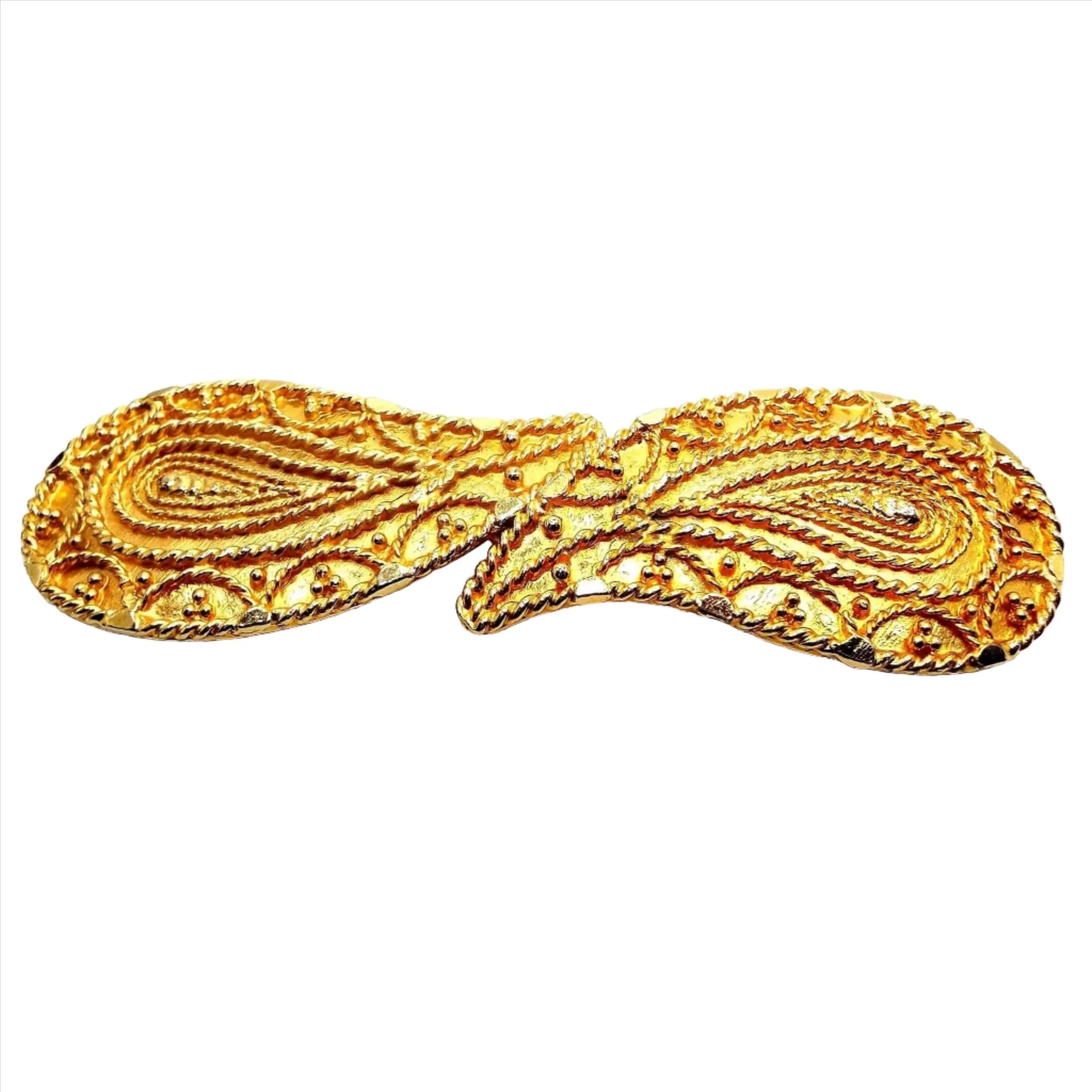 Angled front view of the retro vintage two piece belt buckle. It is gold tone in color and each piece has a detailed paisley design. They look like two teardrops with the pointed ends coming together in the middle.