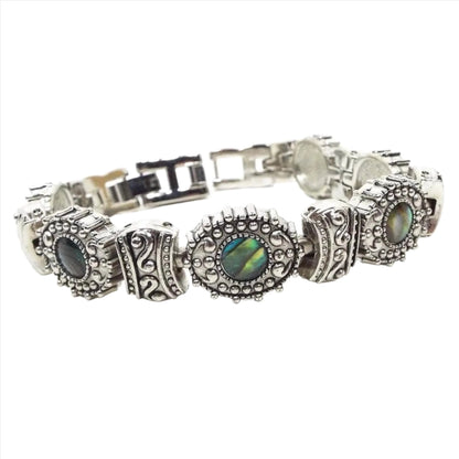 Front view of the retro vintage faux abalone bracelet. The links are antiqued silver tone in color and have a bumpy style pattern on them. Every other link has an imitation abalone cab made of resin. There is a snap lock clasp on the end and an extender link.