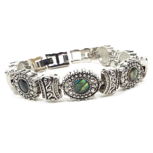 Front view of the retro vintage faux abalone bracelet. The links are antiqued silver tone in color and have a bumpy style pattern on them. Every other link has an imitation abalone cab made of resin. There is a snap lock clasp on the end and an extender link.