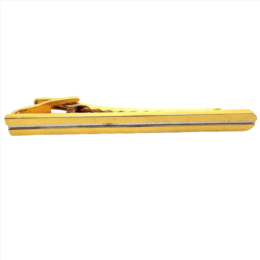 Front view of the Mid Century vintage long two tone tie clip. It is mostly gold tone in color with a thin silver tone indented stripe down the middle.
