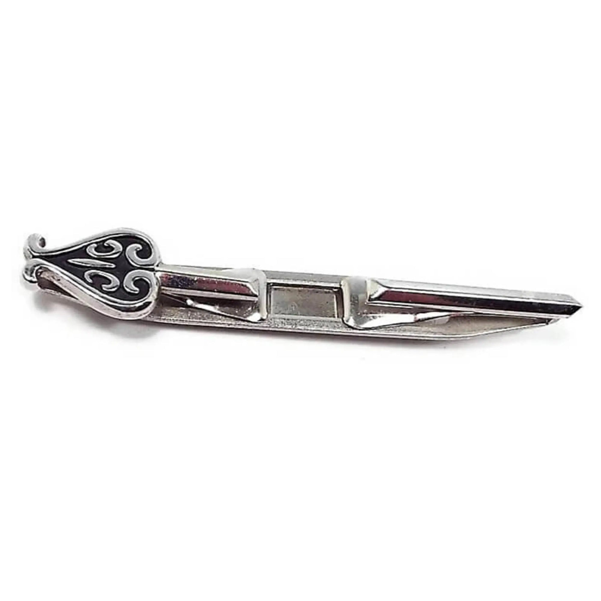 Front view of the Mid Century vintage Swank tie bar. The metal is silver tone in color. There is an open area in the middle for the ends to slide over each side of the tie. One end has a spade like design with black paint.