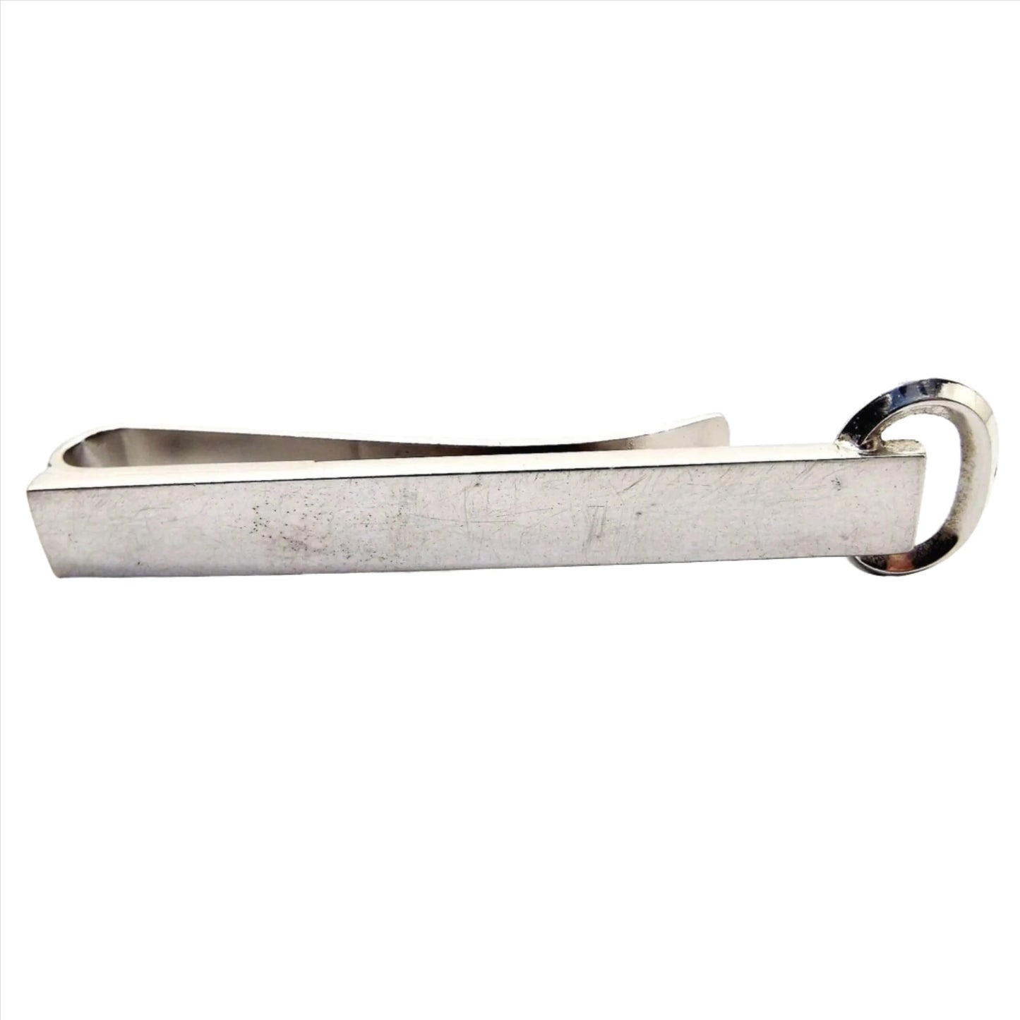 Front view of the silver tone Mid Century vintage Hickok tie bar. It has a long rectangular front with an open oval at the end. It is a slide on style tie bar.