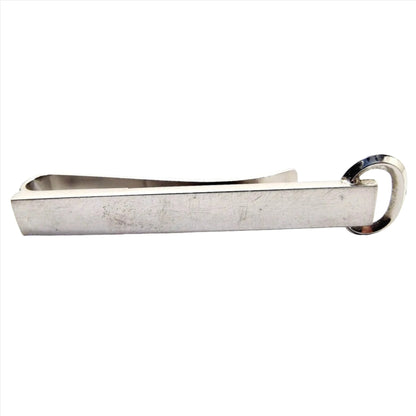 Front view of the silver tone Mid Century vintage Hickok tie bar. It has a long rectangular front with an open oval at the end. It is a slide on style tie bar.