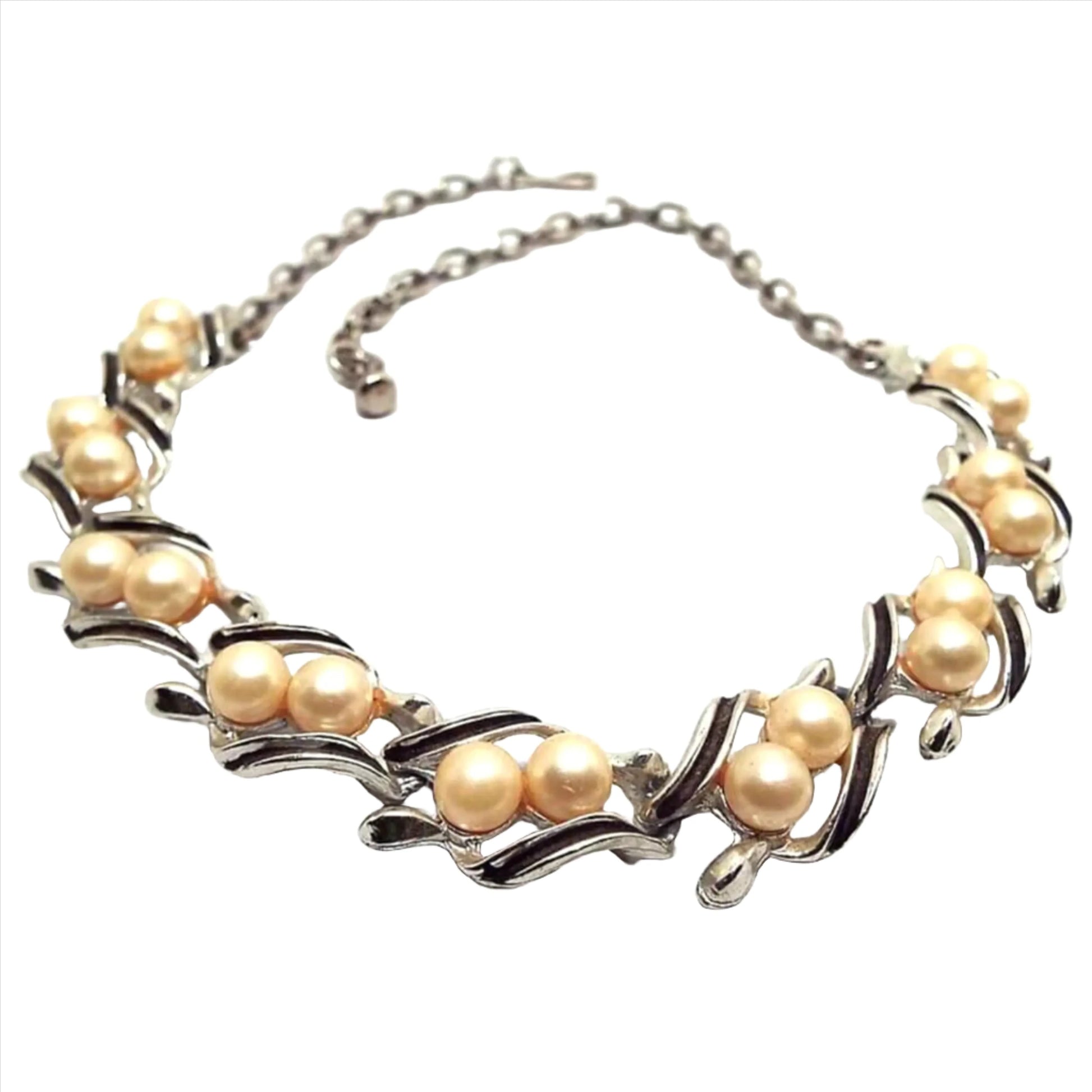 Front view of the Mid Century vintage faux pearl link necklace. The metal is silver tone in color. Each link has two plastic round imitation pearls in off white color and black painted edges on the metal.