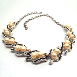 Front view of the Mid Century vintage faux pearl link necklace. The metal is silver tone in color. Each link has two plastic round imitation pearls in off white color and black painted edges on the metal.