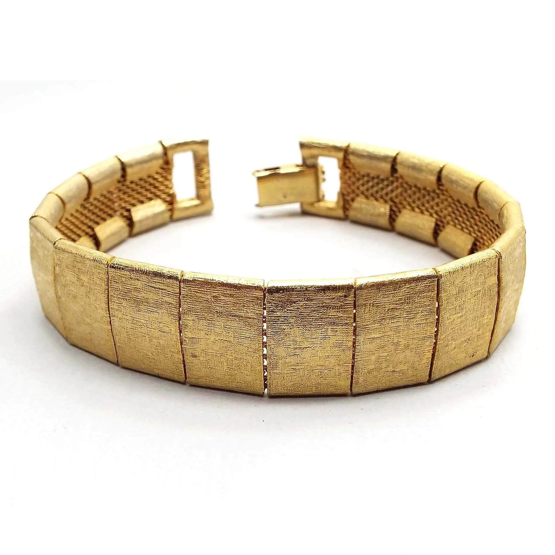 Angled top view of the retro vintage Emmons link bracelet. The bracelet has gold tone color wide links that have a brushed textured matte appearance. There is a snap lock clasp on the end.
