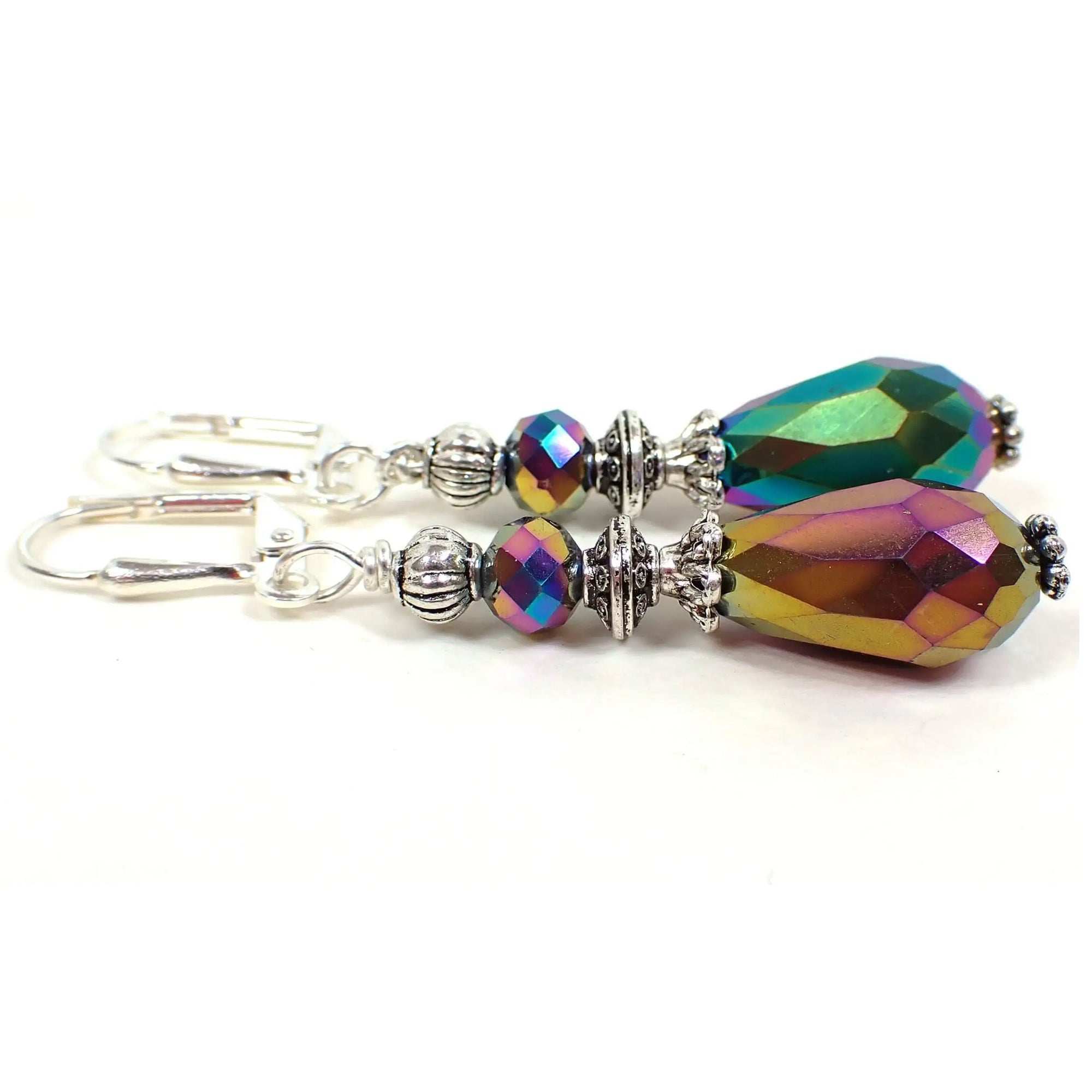 Side view of the handmade metallic rainbow earrings. The metal is silver plated in color. There are faceted glass rondelle beads at the top and teardrop beads at the bottom. The beads are coated with a metallic color pattern that has different colors all the way around the beads. There is purple, yellow, blue, pink, green, and orange.