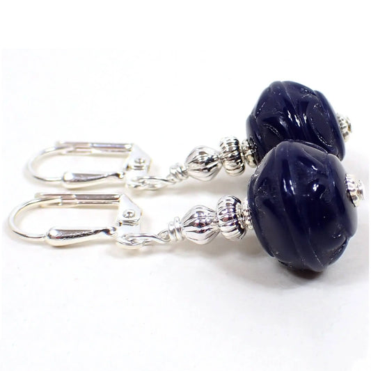 Side view of the handmade drop earrings with vintage lucite beads. The metal is silver plated in color. The bottom lucite beads are rondelle shaped with a textured pattern and are dark blue in color.