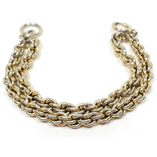 Enlarged view of the Mid Century vintage multi strand chain bracelet. The metal is a light gold tone plated color. There are two strands of wide rope chain attached by a large round jump ring on one end and a large round spring ring clasp on the other.