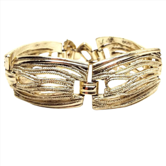 Front view of the Mid Century vintage filigree link bracelet. The metal is gold tone in color. The links are large rectangles with rounded sides and have a cut out filigree design.