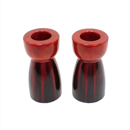 Side view of the handmade resin candlestick holders. They have bright pearly red resin at the top that drips down into pearly black resin at the bottom. The holders have a rounded area on top and a cone like shape underneath that flares out to the bottom.