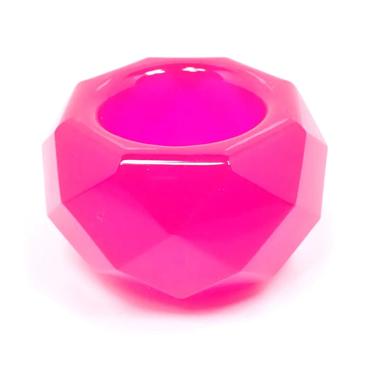 Side view of the small handmade resin geometric succulent pot. The resin is neon pink in color. The piece is shaped like a bowl with an octagon top and faceted edges all the way around. There is a round opening in the middle of the top for small succulents or tiny trinkets.