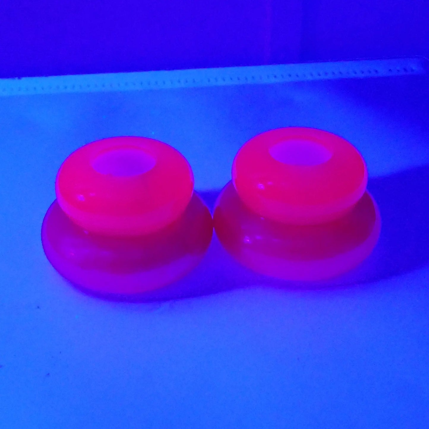 Photo showing how the handmade resin puffy double ring candlestick holders have a fluorescing top under a UV light. 