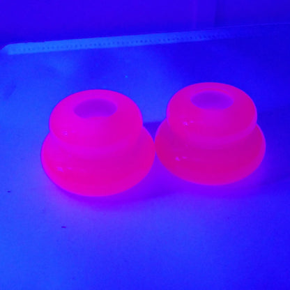 Photo showing how the bright pink handmade resin puffy double ring candlestick holders fluoresce under a UV light. 