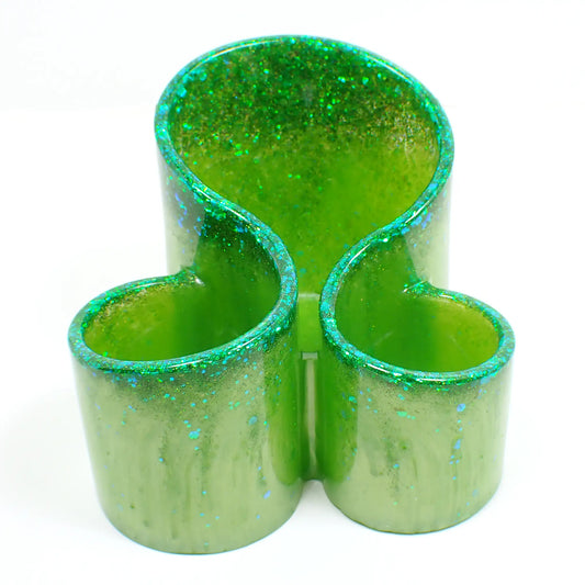 Front view of the handmade resin makeup brush holder. It has lime green resin with iridescent glitter at the top. There are three round areas to hold the brushes with the back having the tallest side.