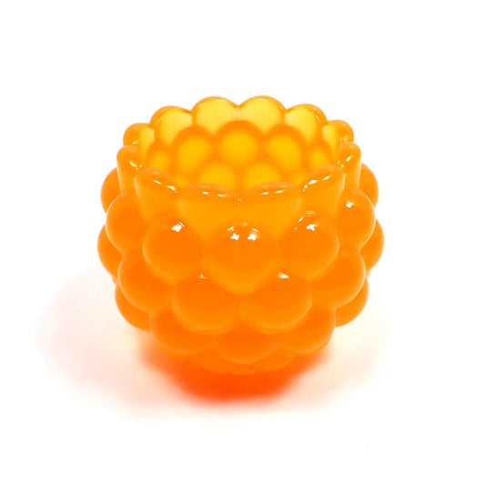 Side view of the handmade resin decorative bowl. The resin is bright neon tangerine orange in color. It has a rounded shape with a bumpy round ball textured on the outside. The top tapers slightly and has a scalloped edge.