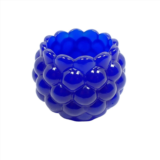 Side view of the handmade resin decorative bowl. The resin is royal blue in color and mostly opaque. It has a rounded shape with a bumpy round ball textured on the outside. The top tapers slightly and has a scalloped edge.