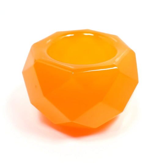 Side view of the small handmade resin geometric succulent pot. The resin is bright neon orange in color. The piece is shaped like a bowl with an octagon top and faceted edges all the way around. There is a round opening in the middle of the top for small succulents or tiny trinkets.