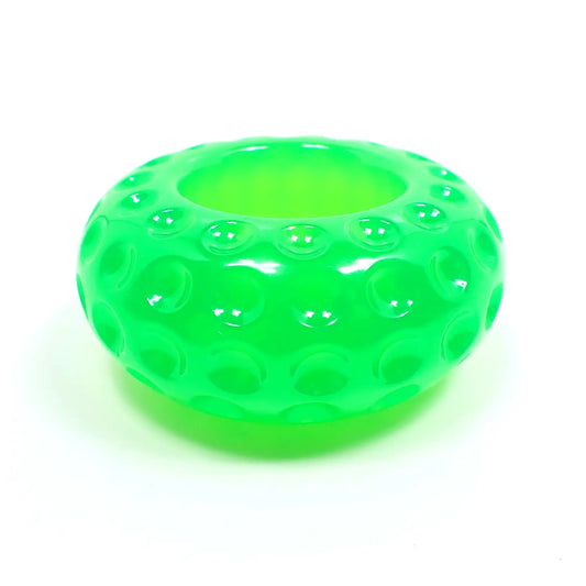 Side view of the small handmade resin succulent pot. It is short round saucer shaped with indented round dots all the way around it. There is an opening at the top for putting a succulent or tiny items. It is bright neon green in color.
